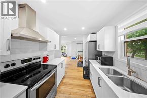 Windsor apartment for rent - A modern kitchen with white cabinets and a black stove top oven.