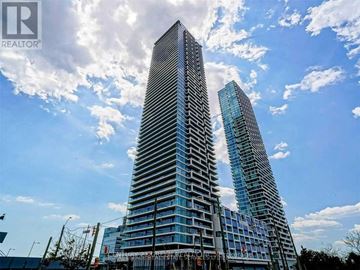 Vaughan (Vaughan Corporate Centre) condo for rent - Two tall buildings with glass windows and balconies are under a blue sky with clouds.