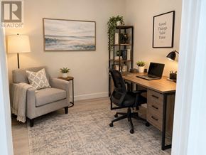 Vaughan (Vaughan Corporate Centre) condo for rent - A well-lit room with a grey sofa, a black chair, a wooden desk with a laptop, and a framed picture on the wall.
