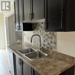 Brampton (Credit Valley) apartment for rent - A kitchen with black cabinets and a checkered backsplash.