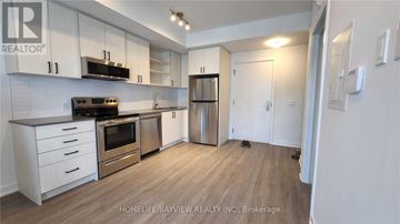 Toronto (Downsview-Roding-Cfb) townhouse for rent - A kitchen with white cabinets and a wooden floor.