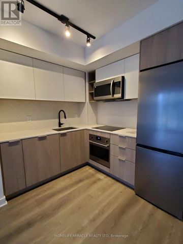 Toronto (Islington-City Centre West) condo for rent - A modern kitchen with wooden cabinets and stainless steel appliances.