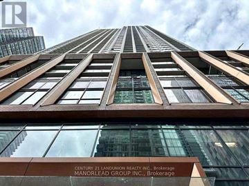 Toronto (Waterfront Communities) condo for rent - A tall building with a glass facade and a sign that reads "Century 21 Landunion Realty Inc., Brokerage Manorlead Group Inc., Brokerage."