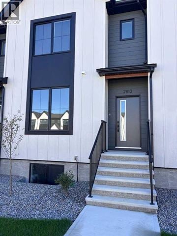 Coaldale apartment for rent - A modern house with a grey front door and a small tree in front.