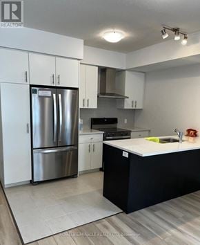 Guelph (Kortright East) townhouse for rent - A modern kitchen with a stainless steel refrigerator and black countertops.