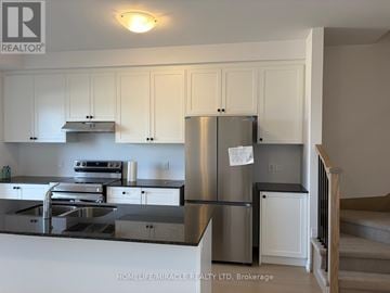 Woodstock (Woodstock - South) townhouse for rent - A kitchen with white cabinets and a stainless steel refrigerator.