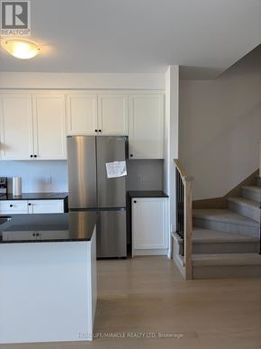 Woodstock (Woodstock - South) townhouse for rent - A kitchen with white cabinets and a stainless steel refrigerator.