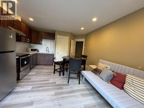 West Vancouver apartment for rent - A well-lit kitchen and dining area with a white sofa and wooden flooring.