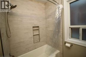 Hamilton apartment for rent - A bathroom with a shower, tub, and window.