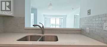 Toronto (Woburn) condo for rent - A modern kitchen with a stainless steel sink and a stone wall.