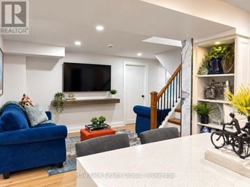 Brampton (Heart Lake West) apartment for rent - A living room with a blue couch and a television mounted on the wall.