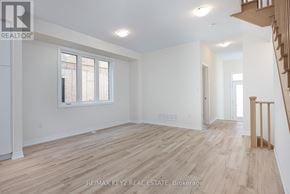 Pickering townhouse for rent - A spacious room with wooden flooring and a staircase on the right side.