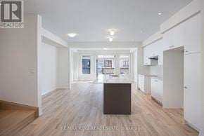 Pickering townhouse for rent - A spacious, well-lit kitchen area with wooden flooring and white walls.