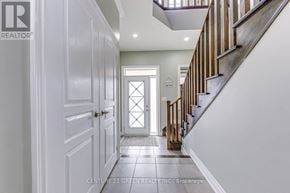 Hamilton (Waterdown) apartment for rent - A hallway with a white door and a staircase with wooden railings.