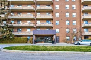 Kitchener condo for rent - A multi-story apartment building with a car parked in front.