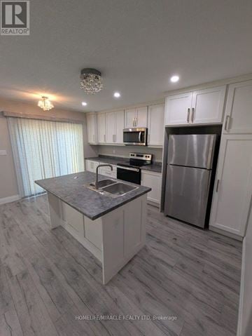 Tillsonburg townhouse for rent - A modern kitchen with a refrigerator, microwave, and oven.