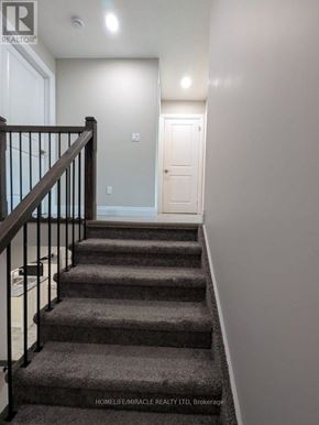 Tillsonburg townhouse for rent - A staircase with a carpeted runner and a black railing.