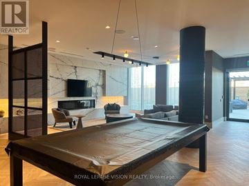 Oshawa (Windfields) condo for rent - A modern living room with a pool table and a television.