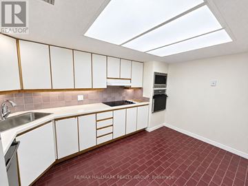 Ottawa condo for rent - A kitchen with white cabinets and a red tile floor.