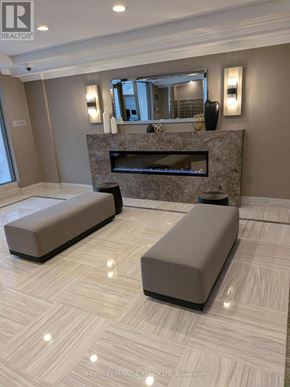 Toronto (Kennedy Park) condo for rent - A living room with a stone fireplace and two grey sofas.