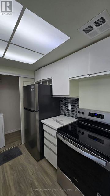 Toronto (Kennedy Park) condo for rent - A kitchen with a black fridge and stove top oven.