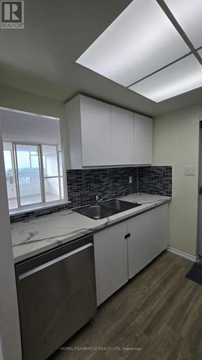 Toronto (Kennedy Park) condo for rent - A kitchen with white cabinets and a black tile backsplash.