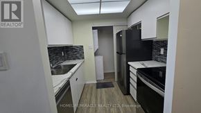 Toronto (Kennedy Park) condo for rent - A kitchen with white cabinets and black appliances.