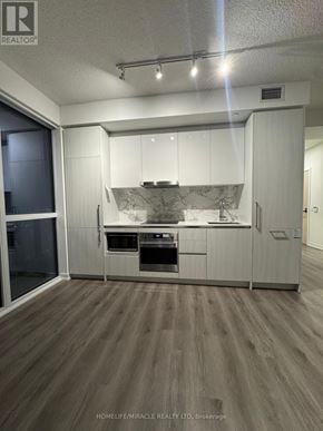 Vaughan (Vaughan Corporate Centre) condo for rent - A modern kitchen with white cabinets and a wooden floor.