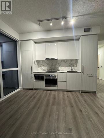 Vaughan (Vaughan Corporate Centre) condo for rent - A modern kitchen with white cabinets and a wooden floor.