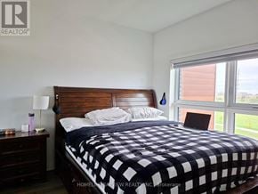 Oakville (Go Glenorchy) condo for rent - A bedroom with a bed, nightstand, and window.