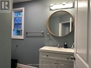 Welland (Welland Downtown) apartment for rent - A bathroom with a round mirror and a light above it.