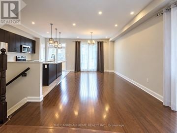 Ottawa apartment for rent - A spacious room with wooden floors and a kitchen area with black cabinets and a microwave.