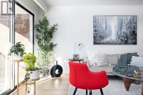 Mississauga (Rathwood) apartment for rent - A red chair sits in a living room with a white couch and a painting on the wall.