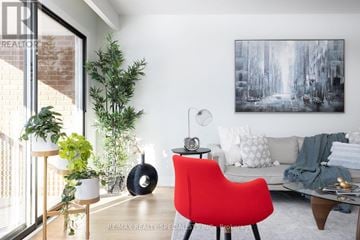 Mississauga (Rathwood) apartment for rent - A red chair sits in a living room with a white couch and a painting on the wall.