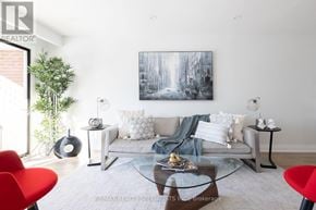 Mississauga (Rathwood) apartment for rent - A living room with a grey couch, a red chair, and a painting on the wall.