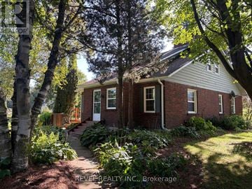 Mono apartment for rent - A house with a red brick exterior and a white trim is surrounded by trees and plants.