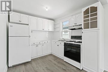 St. Catharines (E. Chester) apartment for rent - A white kitchen with a refrigerator, oven, and cabinets.