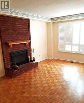 Oshawa (Pinecrest) apartment for rent - A room with a brick fireplace and wooden flooring.