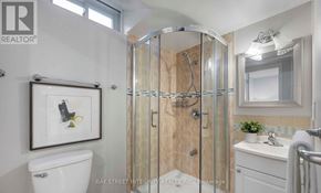 Markham (Milliken Mills East) apartment for rent - A bathroom with a white toilet, a sink, a mirror, and a shower with a glass door.