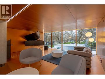 Vancouver apartment for rent - A living room with a white chair and a white bowl on a blue rug.