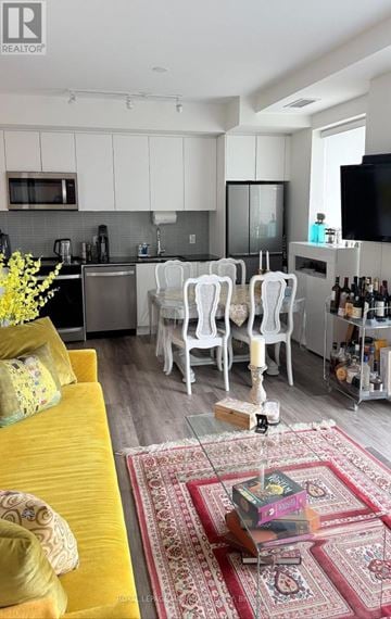 Vaughan condo for rent - A living room with a yellow couch and a rug with a coffee table in front of it.