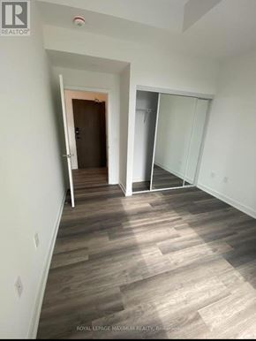 Vaughan condo for rent - A room with wooden flooring and white walls, with a doorway leading to another room.