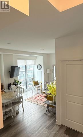 Vaughan condo for rent - A living room with a television, chairs, and a dining table.