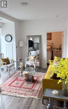Vaughan condo for rent - A living room with a rug, a yellow couch, and a vase of flowers.