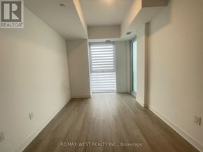 Hamilton (Riverdale) condo for rent - A spacious room with wooden flooring and a large window with blinds.