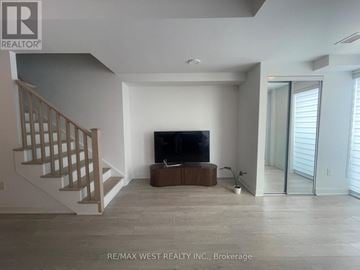 Hamilton (Riverdale) condo for rent - A spacious living room with a television and a staircase.