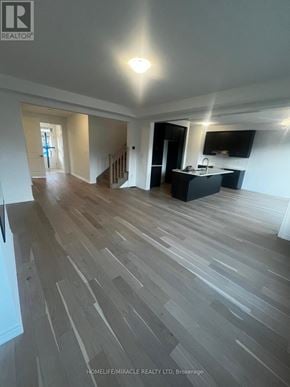 Barrie (Painswick South) apartment for rent - A spacious room with wooden flooring and a kitchen area.