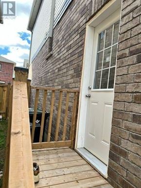 North Dumfries apartment for rent - A wooden deck leads to a white door on a brick building.