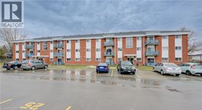Waterloo condo for rent - A parking lot with cars and a building in the background.