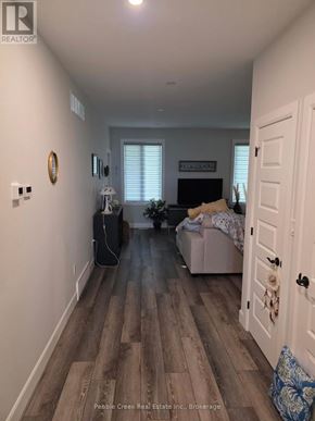 Goderich (Goderich (Town)) apartment for rent - A hallway with a door on the right and a couch with a blanket on it in the background.